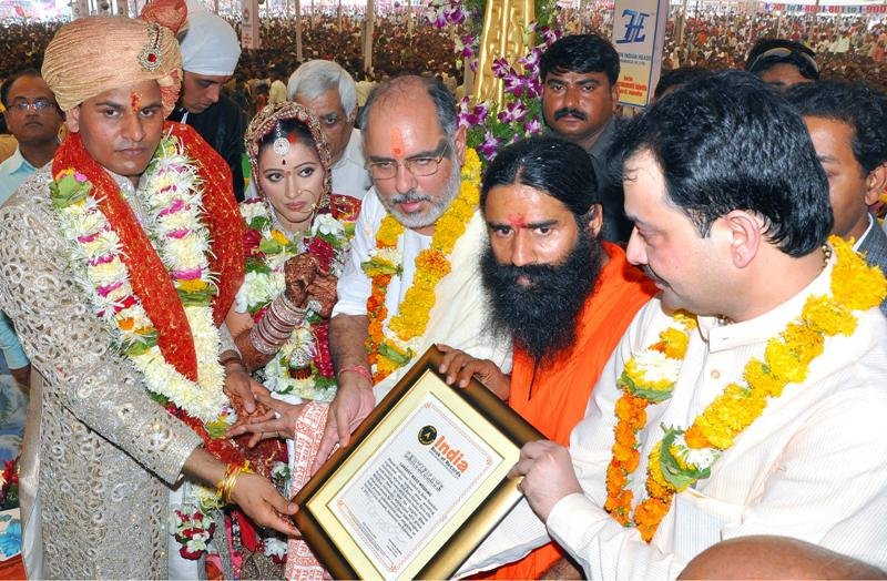 A picture of Ravi Rana and Navneet Rana on their wedding day, along with Baba Ramdev, receiving the India Book of Records Certificate for Largest Mass Wedding