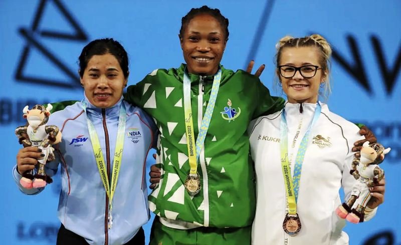 Nigeria's Adijat Adenike Olarinoye, center, silver medalist India's Bindyarani Devi Sorokhaibam, left, and bronze medalist England's Fraer Morrow on the podium at 2022 Commonwealth Games